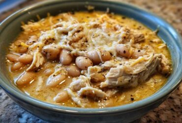 Close-up of a bowl of creamy white chicken chili featuring shredded chicken, white beans, and melted cheese topping.