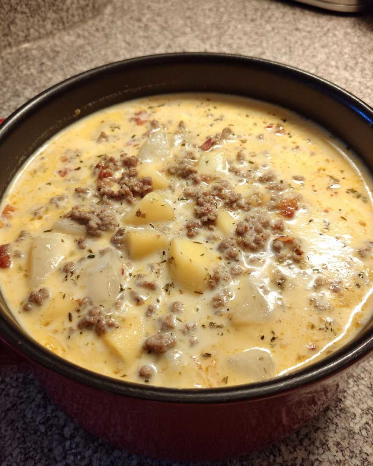 Close-up of creamy sausage potato soup featuring chunks of potato and ground sausage in a rich broth.