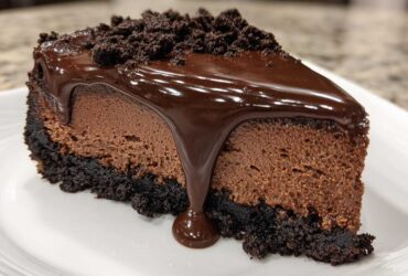 A close-up of a rich slice of chocolate cheesecake with a dark crust, mousse layer, and dripping ganache.