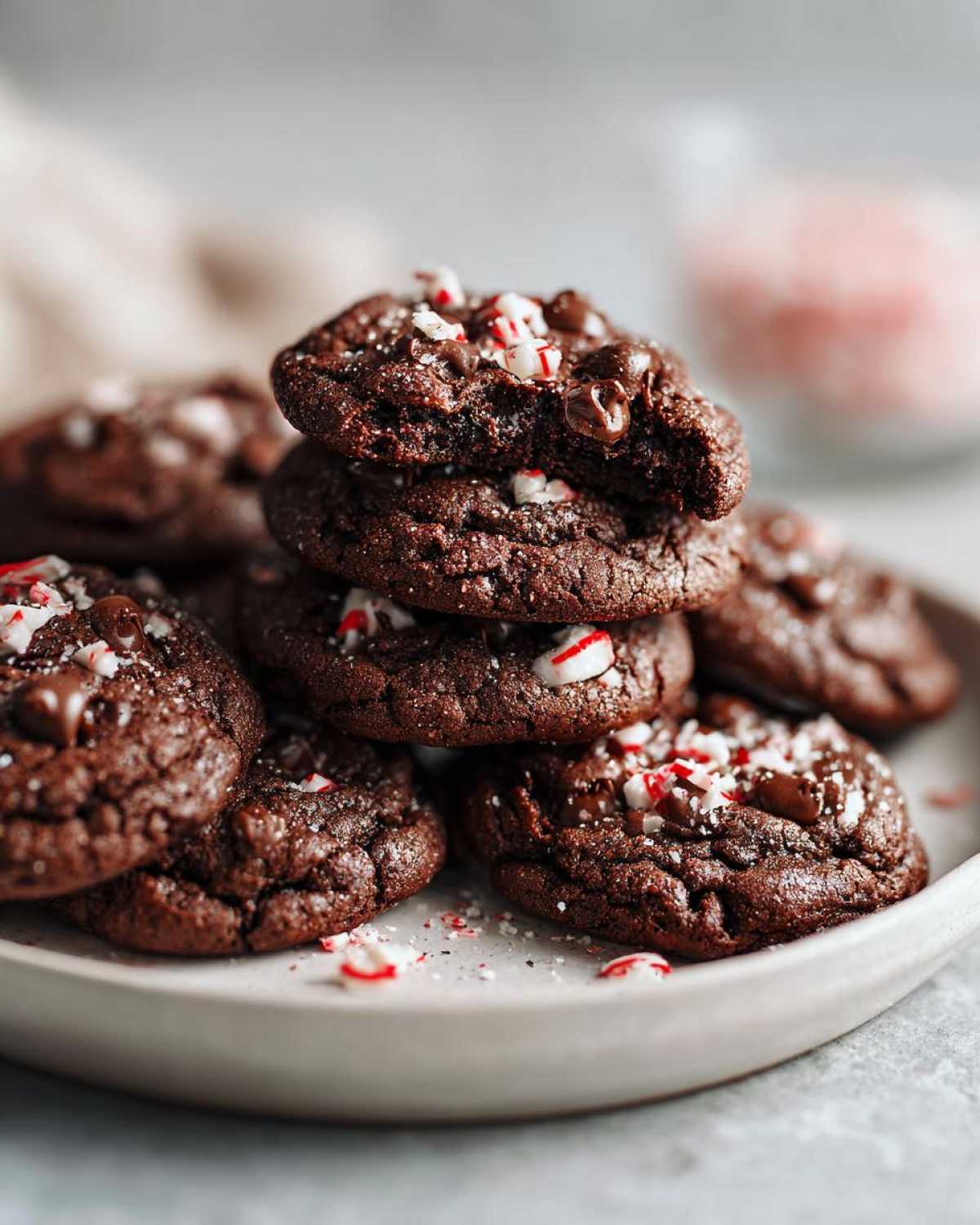 A stack of rich, fudgy double chocolate peppermint cookies topped with crushed candy canes.
