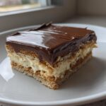 A single serving slice of an amazing 15-minute eclair cake featuring layers of graham crackers, cream filling, and chocolate frosting.