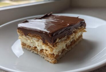 A single serving slice of an amazing 15-minute eclair cake featuring layers of graham crackers, cream filling, and chocolate frosting.