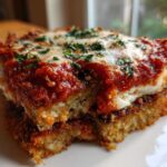 Close-up of a serving of crispy eggplant parmesan topped with rich tomato sauce and melted mozzarella cheese.