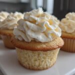 Close-up of a perfectly baked vanilla cupcake topped with a swirl of rich white vanilla frosting.