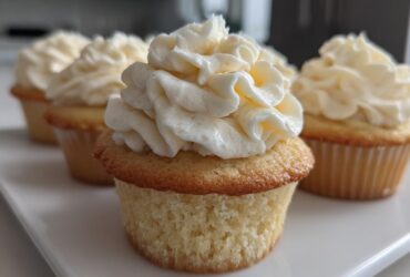 Close-up of a perfectly baked vanilla cupcake topped with a swirl of rich white vanilla frosting.