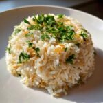 A mound of fluffy rice pilaf, featuring toasted vermicelli and fresh parsley garnish, served on a white plate.