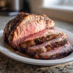 Close-up of a beautifully roasted prime rib recipe, sliced to show a perfect medium-rare center and herb crust.