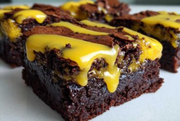 Close-up of a fudgy, dark chocolate Lemon Brownies square topped with a thick, bright yellow lemon glaze drizzle.