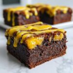 Close-up of a fudgy Lemon Brownies square topped with a vibrant yellow lemon glaze drizzle.
