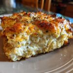Close-up of a golden-brown slice of Garlic parmesan chicken bake with a creamy, cheesy interior.