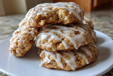 A stack of delicious apple pie cookies drizzled with white icing, one cookie on top has a bite taken out.