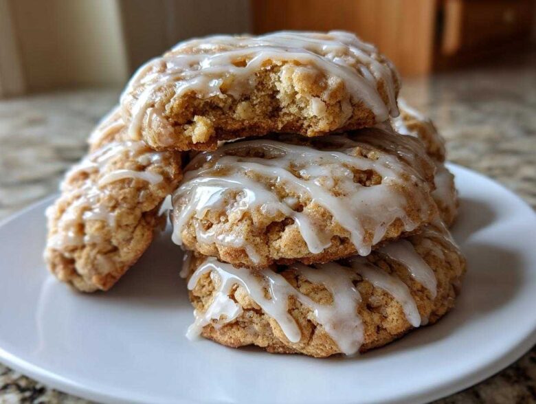 A stack of delicious apple pie cookies drizzled with white icing, one cookie on top has a bite taken out.