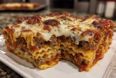 Close-up of a hearty slice of pizza casserole showing layers of pasta, meat sauce, and melted cheese.