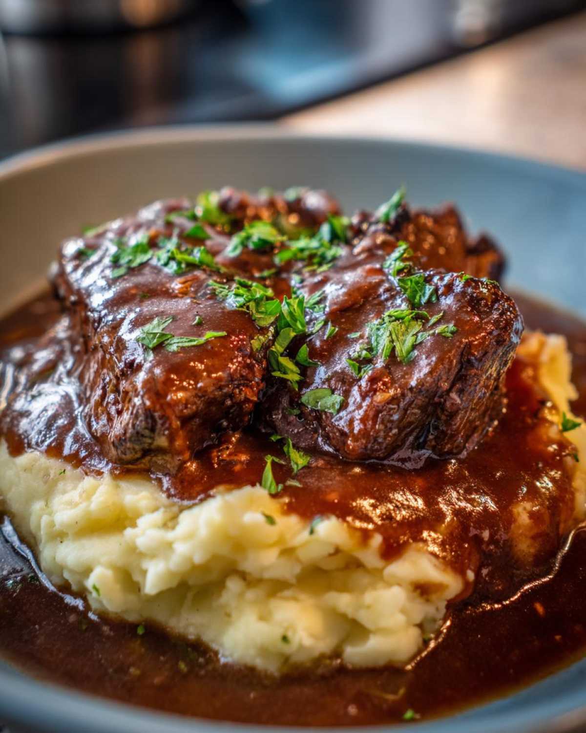 Close-up of tender meat smothered in rich homemade brown gravy served over mashed potatoes and garnished with parsley.