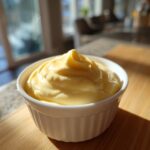 A close-up of rich, creamy homemade mayonnaise, perfectly whipped and sitting in a small white ramekin.
