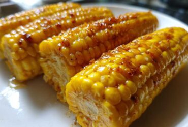 Three pieces of glistening, glazed corn on the cob coated in honey butter and spices.