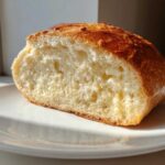 A close-up view of a slice of homemade italian bread showing the soft, airy interior crumb and golden-brown crust.