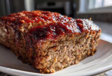 Close-up of a juicy Keto meatloaf loaf with one slice cut, showing the texture and shiny glaze.