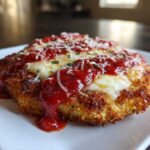 Close-up of a perfectly breaded keto chicken parmesan topped with melted mozzarella and marinara sauce.