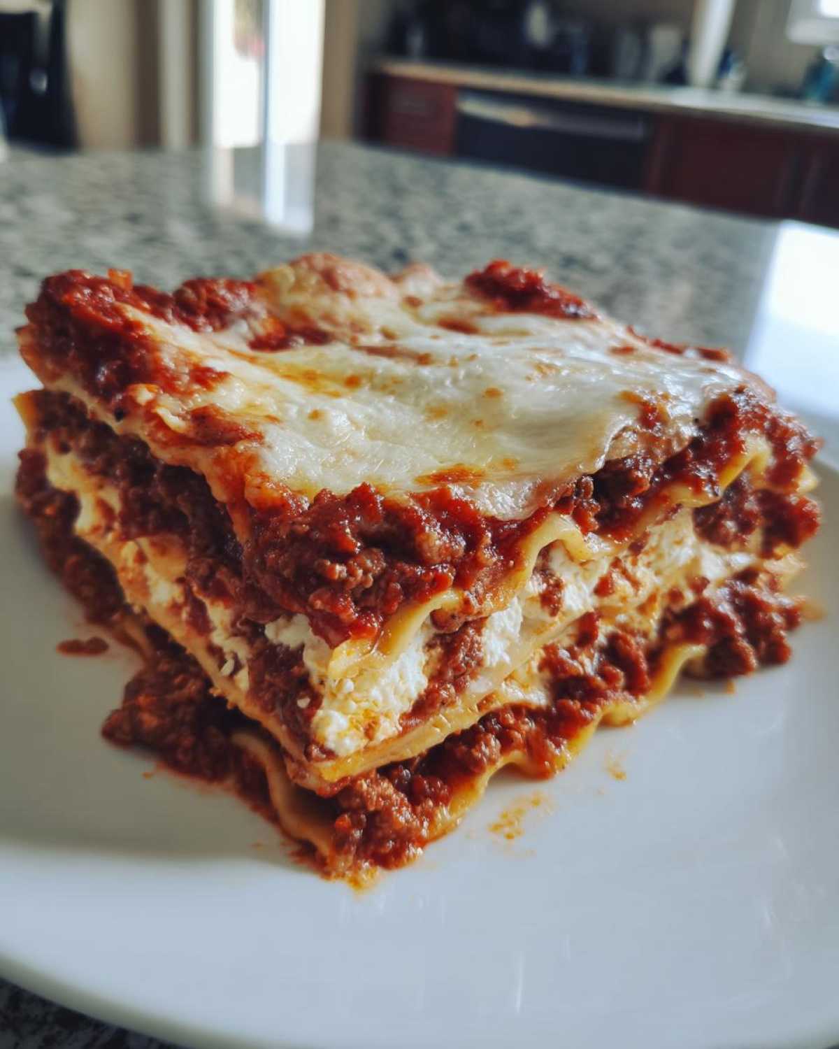 A close-up of a hearty slice of lasagna with cottage cheese, rich meat sauce, and melted mozzarella topping.