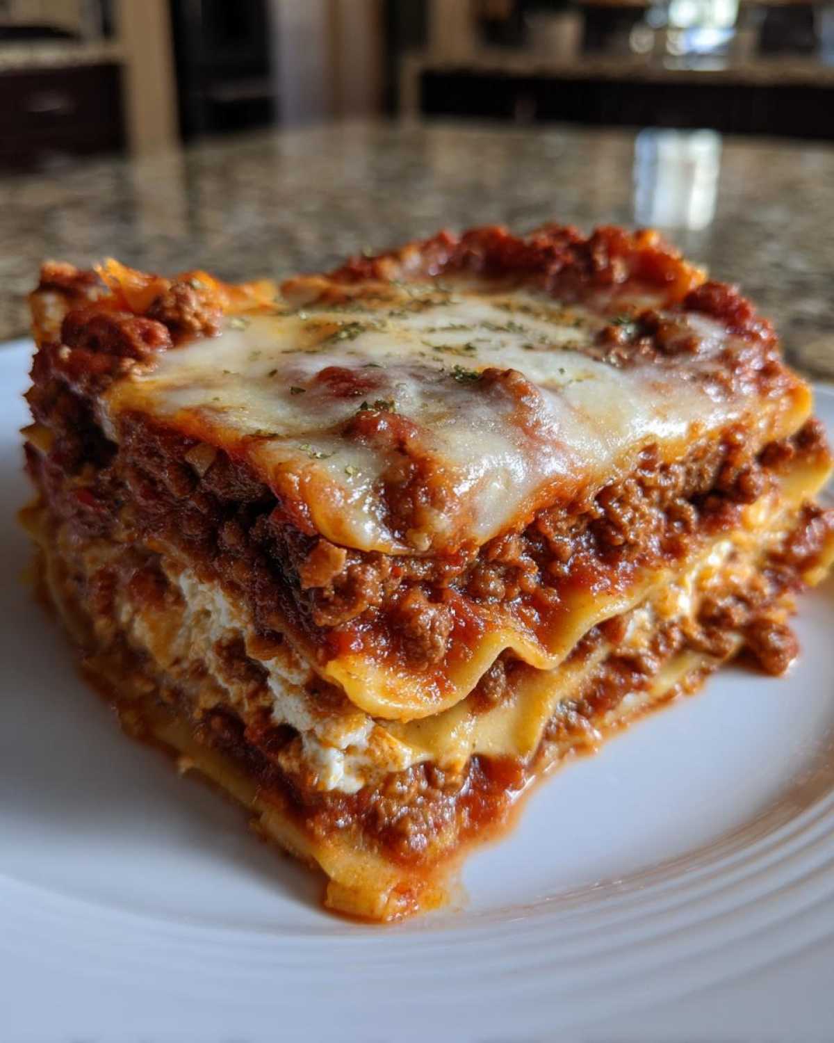 A thick, layered slice of Lasagna with Cottage Cheese topped with melted mozzarella and herbs.