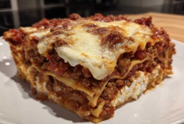 A thick, layered slice of lasagna with cottage cheese, meat sauce, and melted cheese topping.