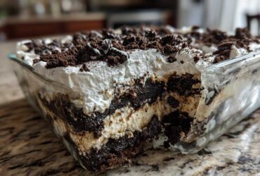 A close-up view showing the layers of creamy filling and crushed cookies in a glass dish of oreo dirt cake.