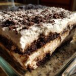 Close-up of a rich, layered slice of oreo dirt cake showing chocolate cookie crumbs and cream filling.