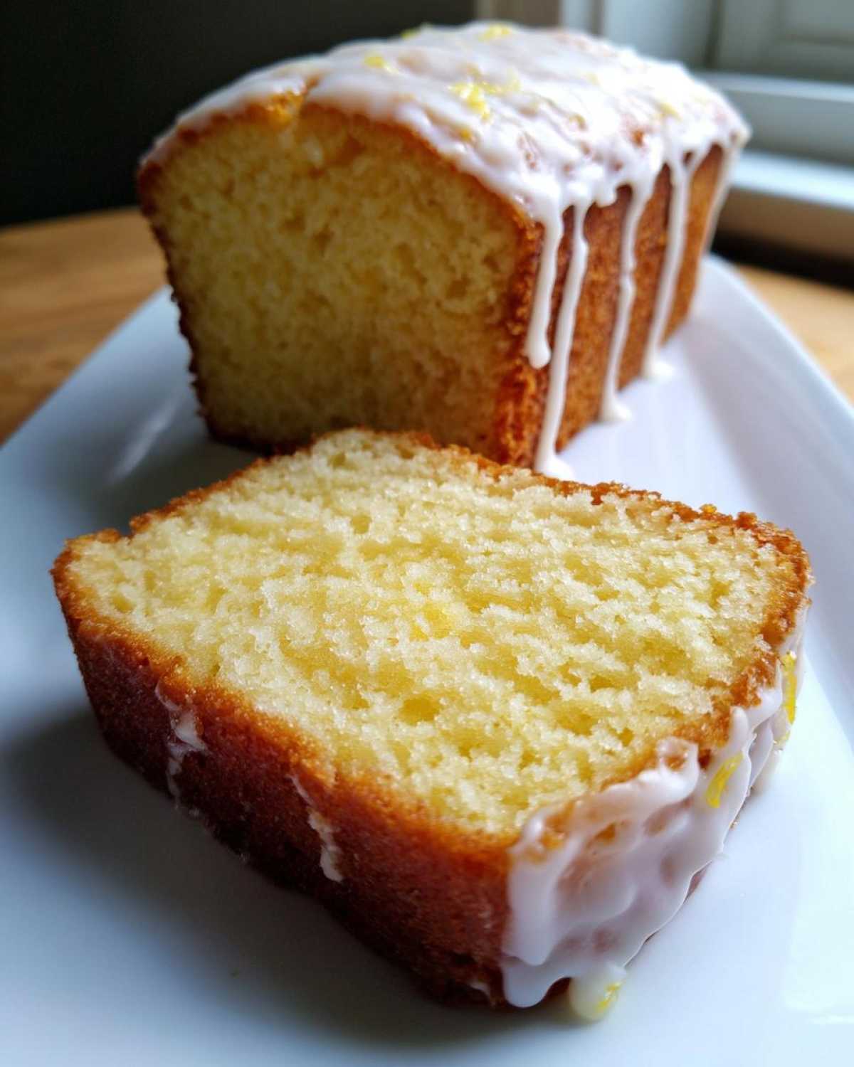 Close-up of a moist slice of lemon pound cake topped with dripping white lemon glaze.