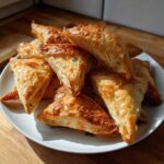 A pile of golden brown, flaky Mediterranean Spinach and Feta Cheese Crisps served on a white plate.