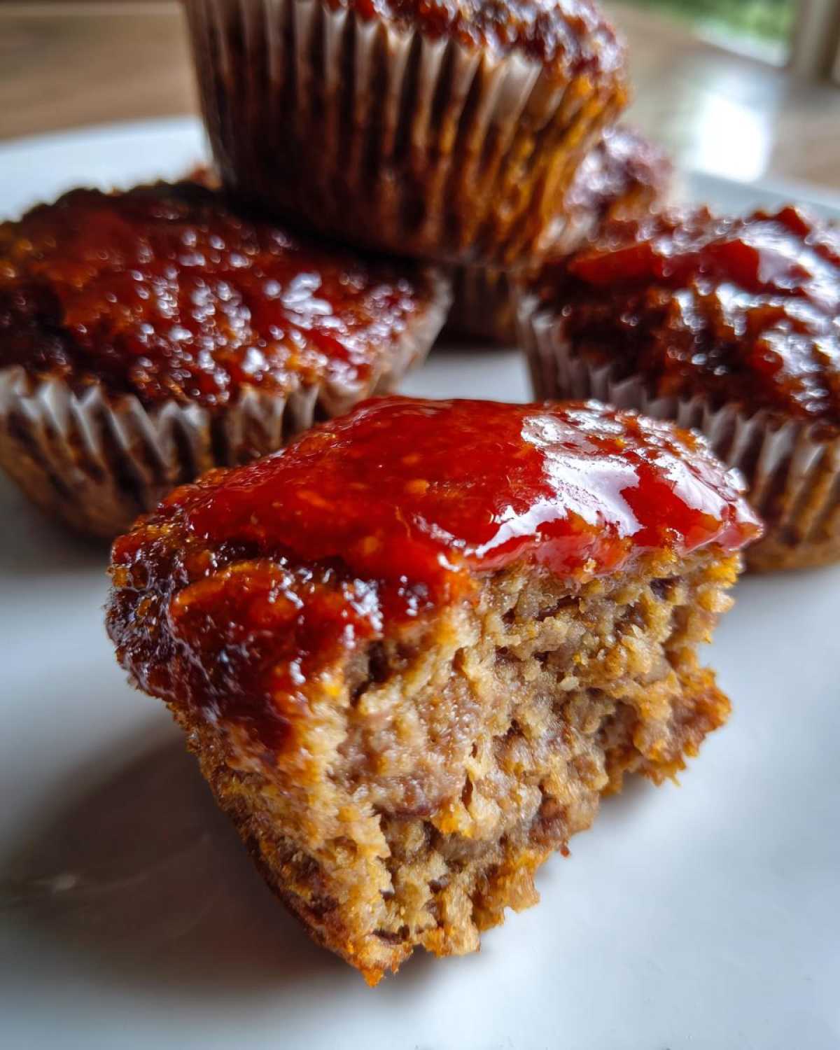 A bite taken out of a glazed mini meatloaf muffin showing the texture inside.
