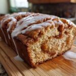 Close-up of a loaf of freshly baked apple fritter bread, drizzled with white vanilla glaze.