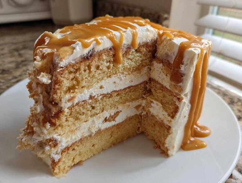 Close-up of a slice of moist caramel cake showing three layers of cake and frosting, topped with thick caramel drizzle.