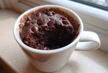 Close-up of a moist chocolate mug cake topped with chocolate chips, ready to eat.