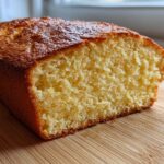 A close-up view of a freshly baked loaf of condensed milk bread showing its golden crust and soft, yellow crumb.