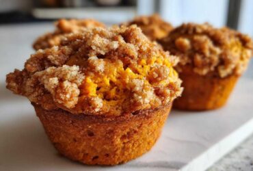 Close-up of a moist sweet potato muffins featuring a thick, sugary cinnamon crumb topping.
