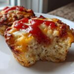 A close-up shot showing a bite taken out of one of the amazing 15-minute Pizza Muffins, topped with melted cheese and a dollop of ketchup.