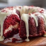 A slice cut out of a moist red velvet bundt cake topped with dripping cream cheese glaze.