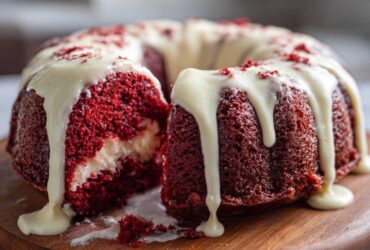 A slice cut out of a moist red velvet bundt cake topped with dripping cream cheese glaze.