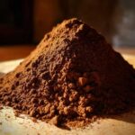 Close-up of a mound of rich brown hot cocoa mix powder, dramatically lit.