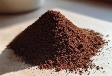Close-up of a small mound of dark brown, finely ground hot cocoa mix powder on a light surface.
