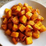Close-up of perfectly caramelized roasted butternut squash cubes seasoned with herbs.