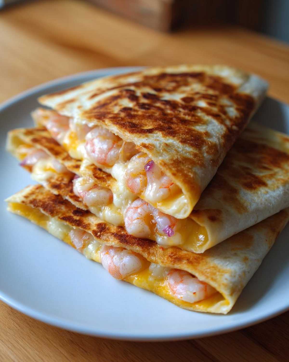 A stack of golden-brown shrimp quesadilla wedges oozing with melted cheese and visible pink shrimp.