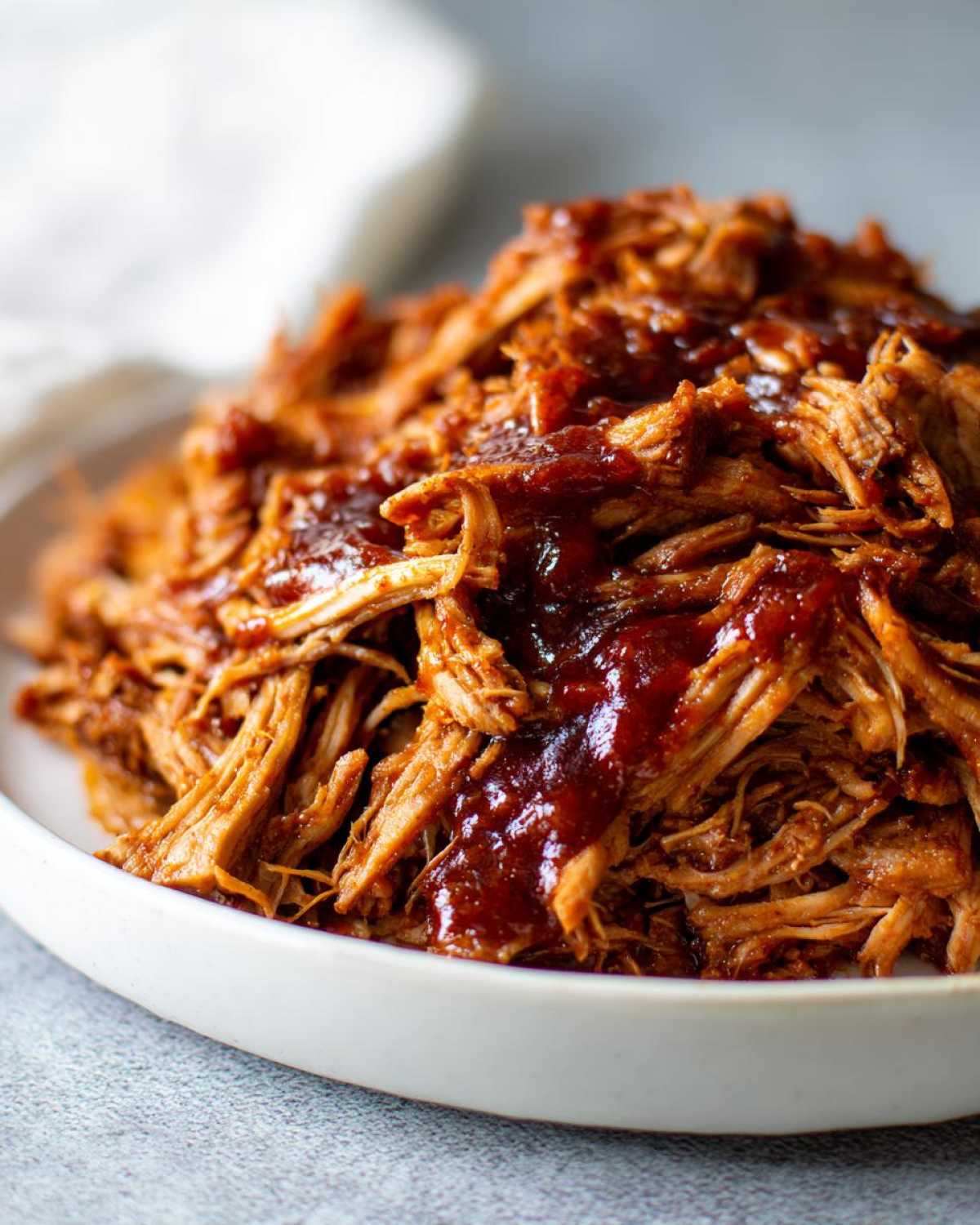 A close-up shot of tender, shredded Slow cooker pulled pork generously coated in rich barbecue sauce.