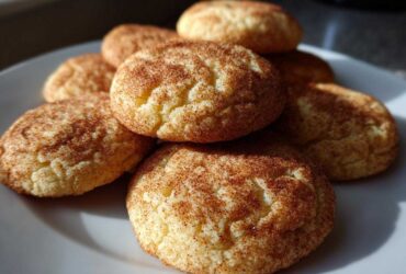 A stack of soft, chewy snickerdoodles cookies generously coated in cinnamon sugar on a white plate.