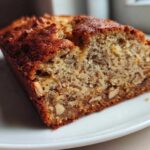 Close-up of a slice of moist sugar free banana bread showing the crumb texture and visible nuts.