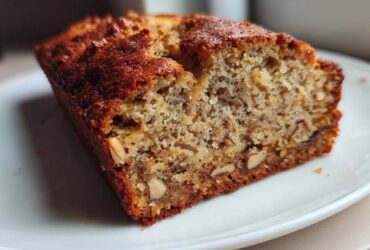 Close-up of a slice of moist sugar free banana bread showing the crumb texture and visible nuts.