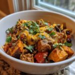 Close-up of a hearty sweet potato skillet bowl topped with melted cheddar cheese, black beans, and fresh cilantro.