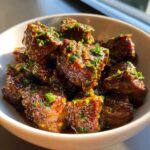 Close-up of tender crockpot steak bites coated in a glossy, savory sauce and topped with fresh parsley.