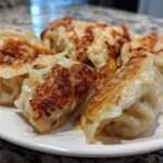 A plate of perfectly pan-fried Traditional Chinese Dumplings with golden-brown crispy bottoms.